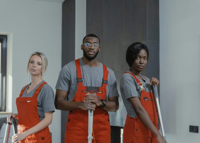 A diverse team of cleaning professionals in uniform posing in an indoor setting.